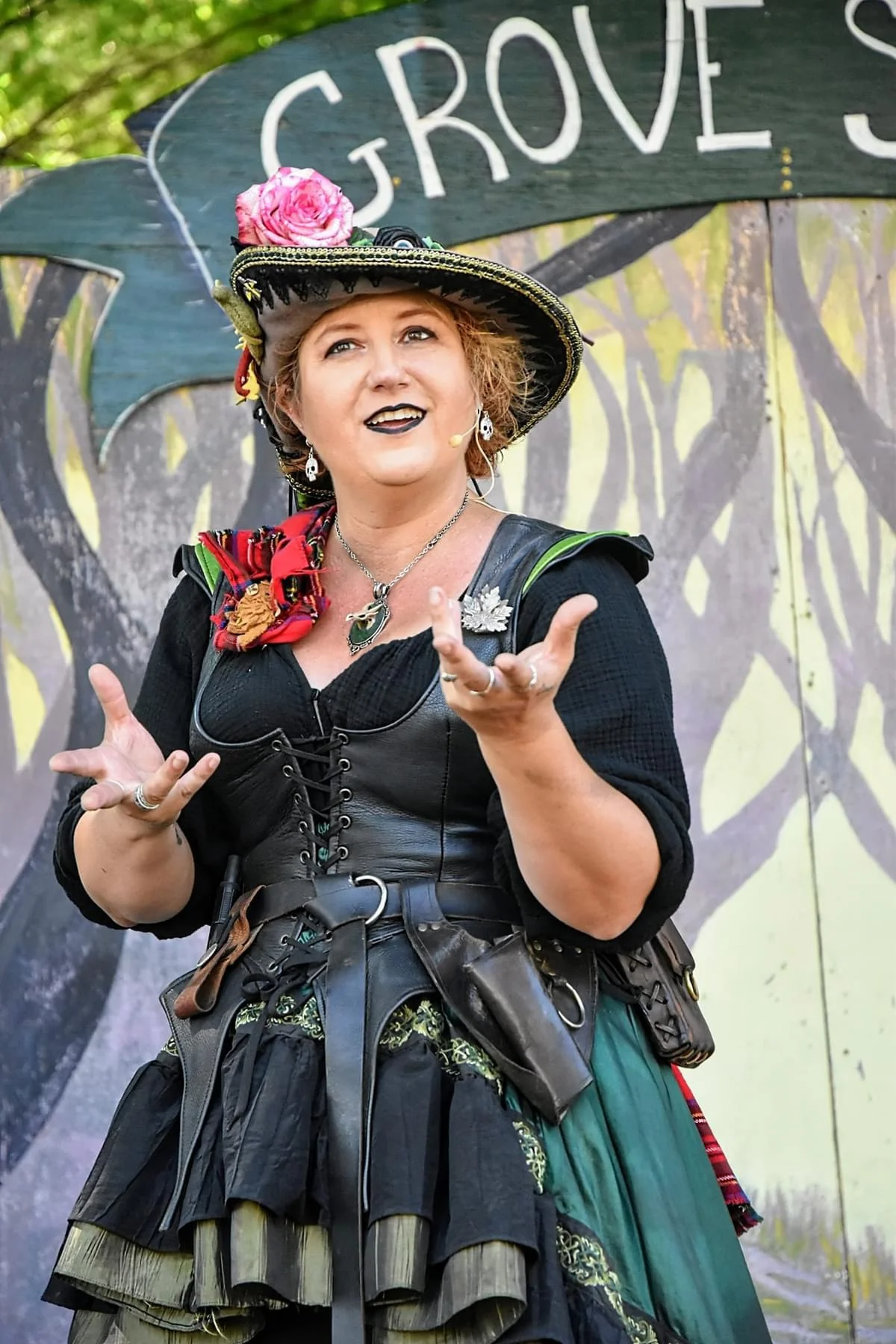 Performer in period costume with sword, smiling at camera during outdoor renaissance faire performance
